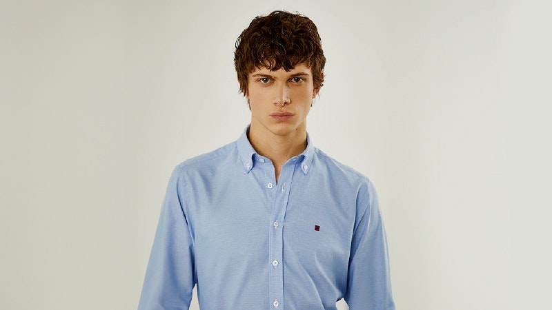 modelo a usar camisa lisa e de corte slim fit, azul clara